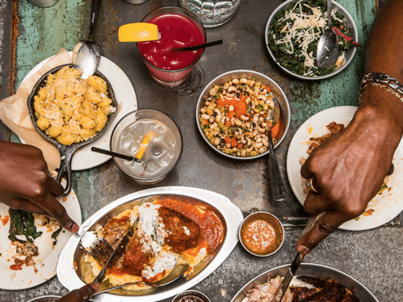 Overhead photo of Super Mega Bien on a customer's table. A set of hands is in the shot, already digging into their meal.