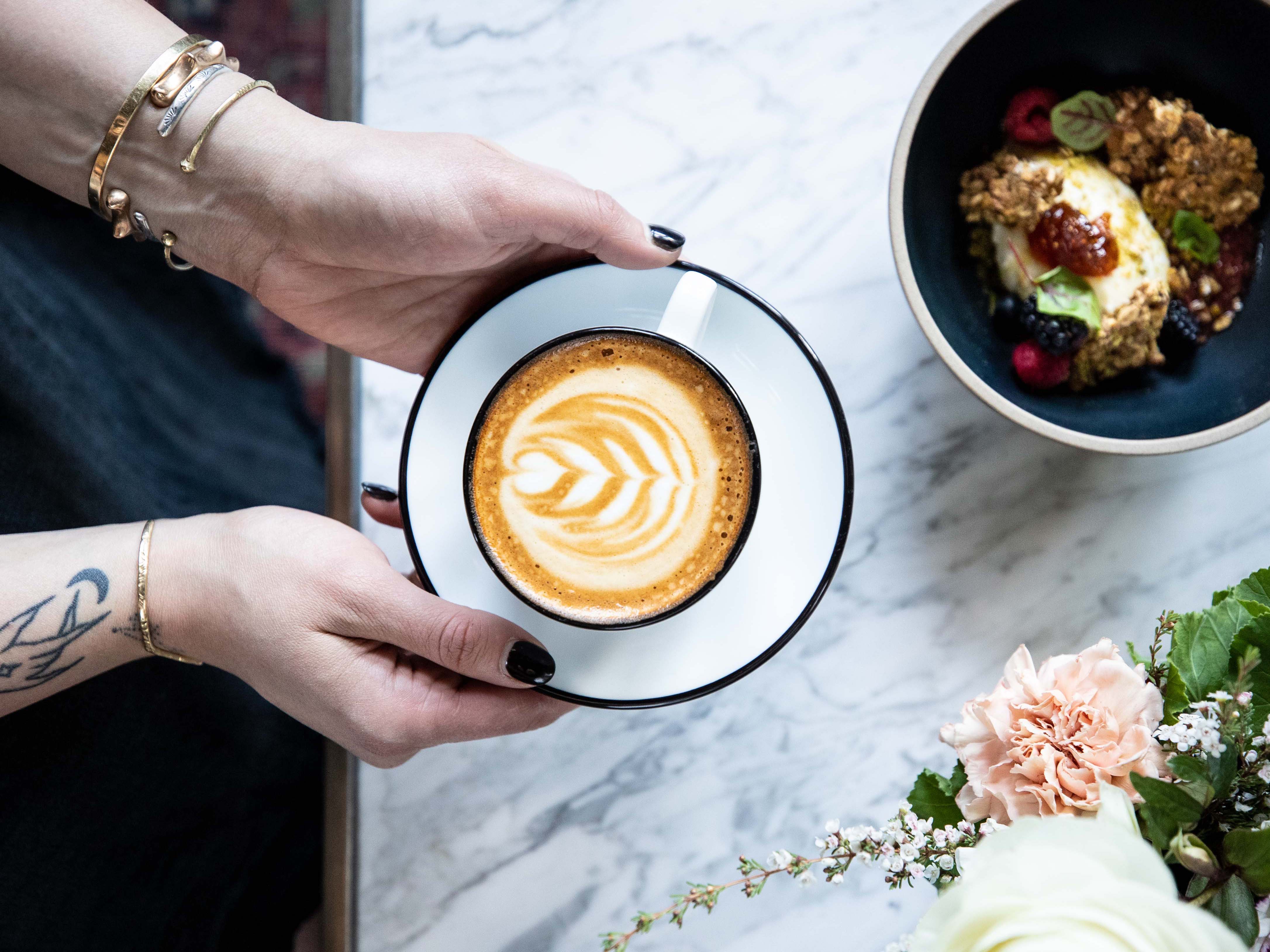 Overhead shot of a woman holding a cappuccino inside DC/AM.